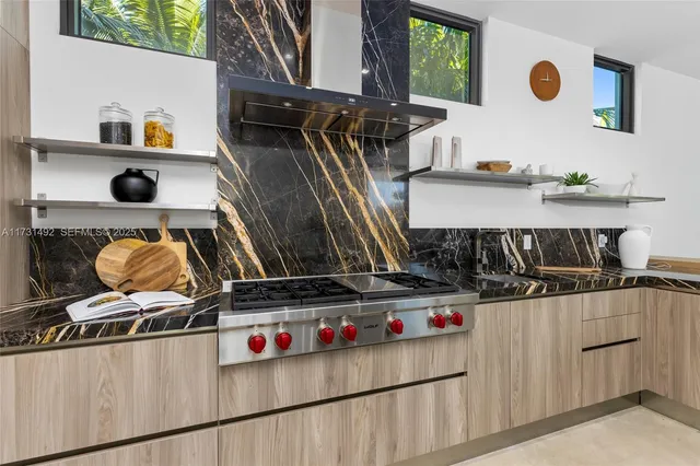 a kitchen with stainless steel appliances kitchen island granite countertop a table chairs and a refrigerator