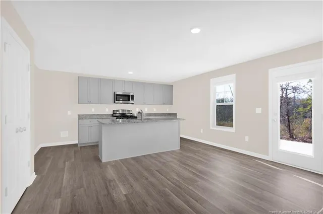 a kitchen with granite countertop wooden floors stainless steel appliances and sink