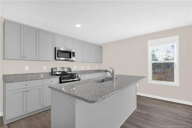a kitchen with granite countertop a sink a stove and cabinets