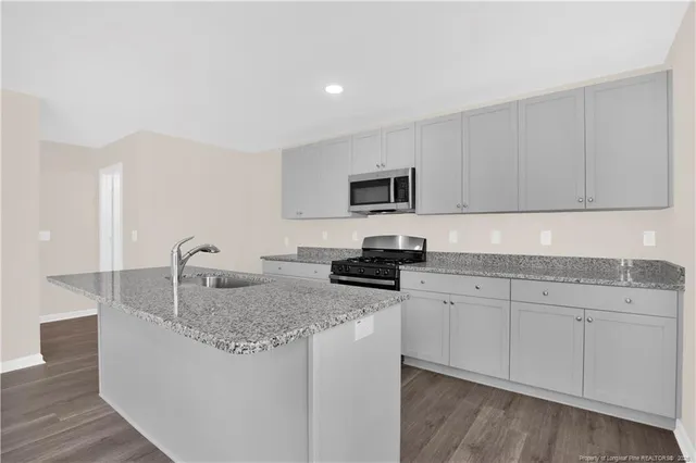 a kitchen with kitchen island granite countertop a sink a stove and cabinets