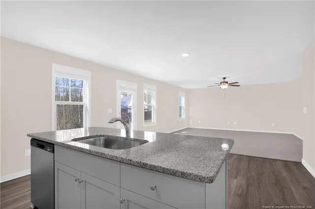 a kitchen with a sink dishwasher and a refrigerator with wooden floor