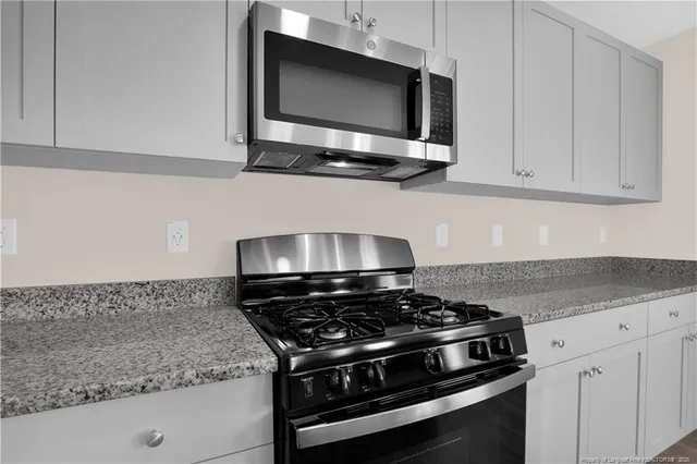 a kitchen with stainless steel appliances granite countertop white cabinets and stove
