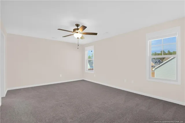 an empty room with windows and chandelier fan