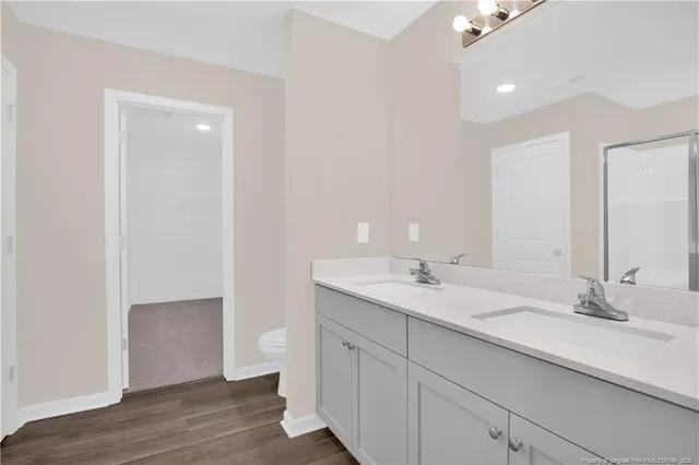 a bathroom with a double vanity sink toilet and a mirror
