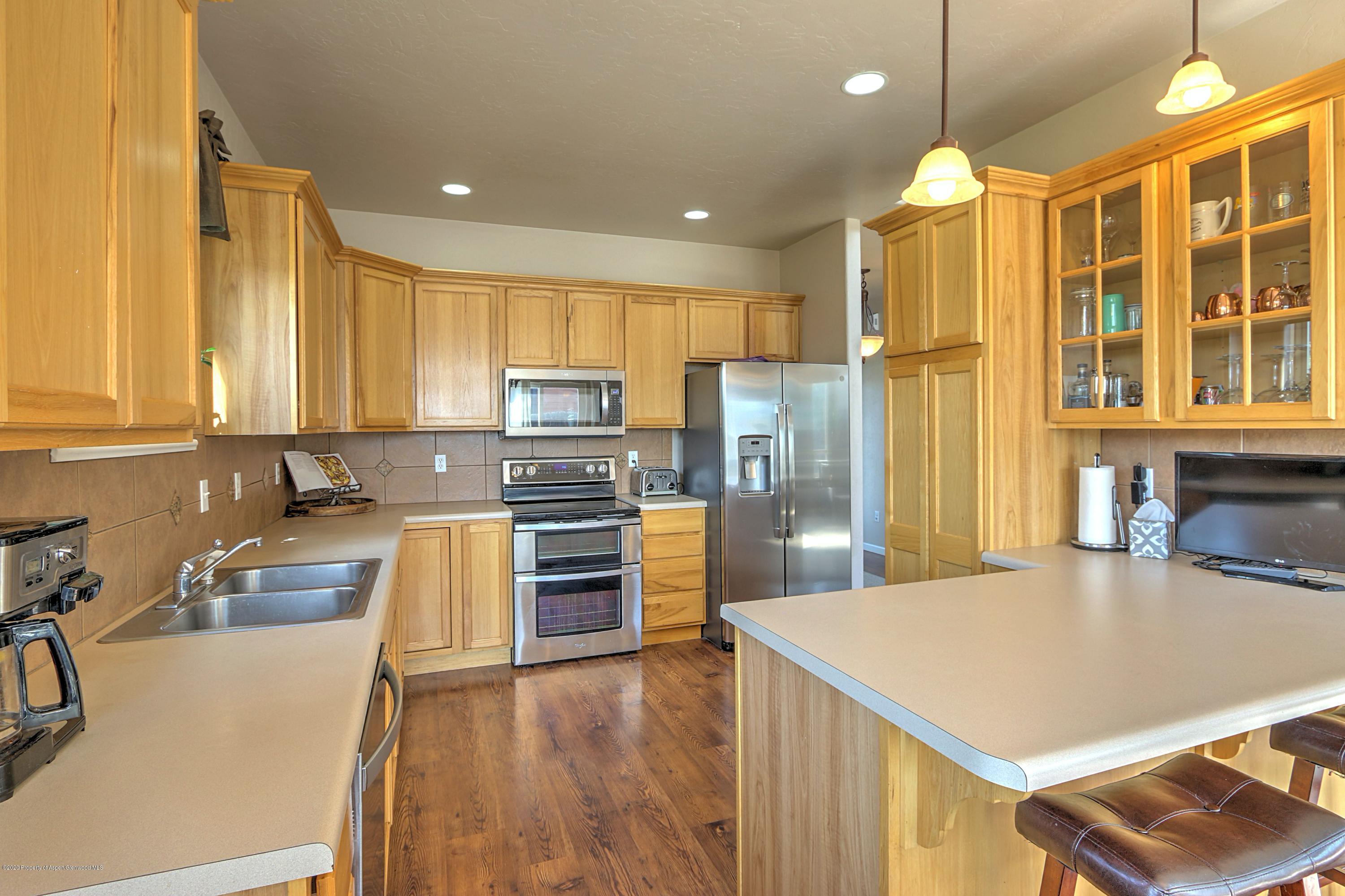 1600 Anvil View Avenue Rifle, CO 81650 - Photo 5 of 22 a kitchen with stainless steel appliances a refrigerator a stove a sink a center island and couches with wooden floor