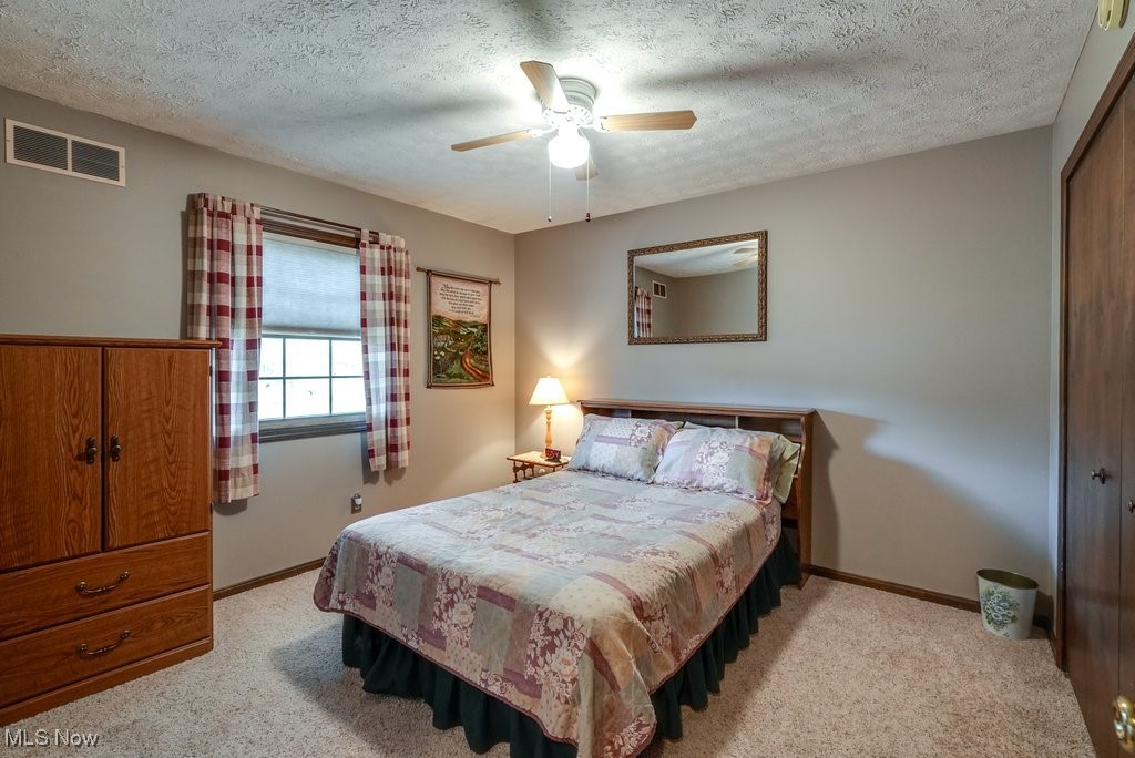 2573 Killian Road Uniontown, OH 44685 - Photo 26 of 40 Bedroom featuring a closet, a textured ceiling, light colored carpet, and ceiling fan