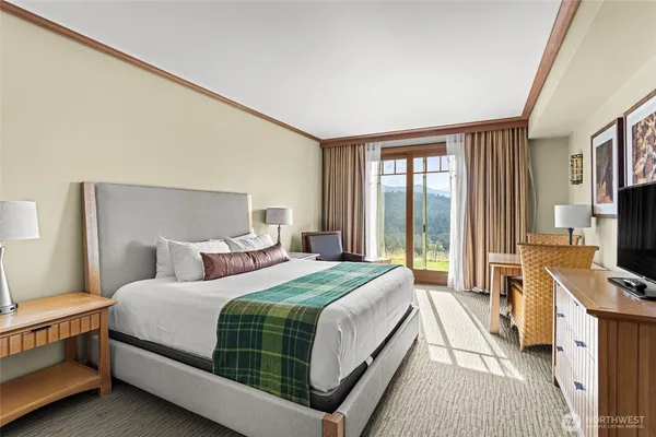 a bedroom with a bed and a flat tv screen on dresser