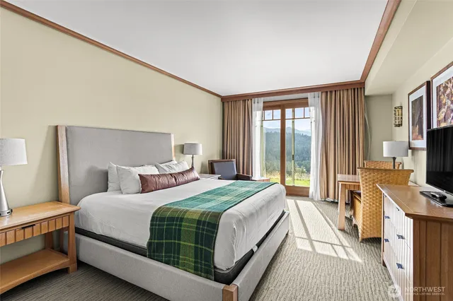 a bedroom with a bed and a flat tv screen on dresser