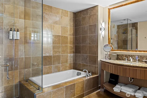 a bathroom with a tub a sink a mirror and shower
