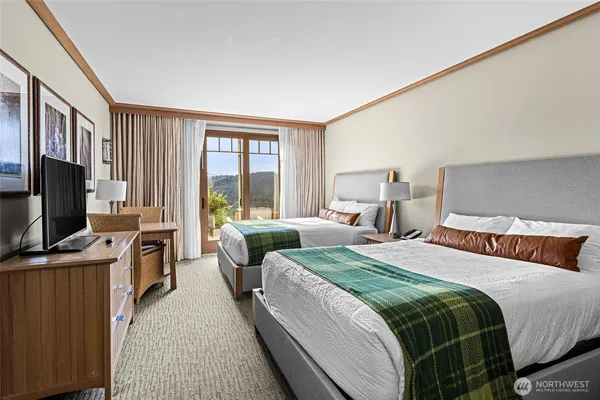 a bedroom with a bed and a flat tv screen on dresser
