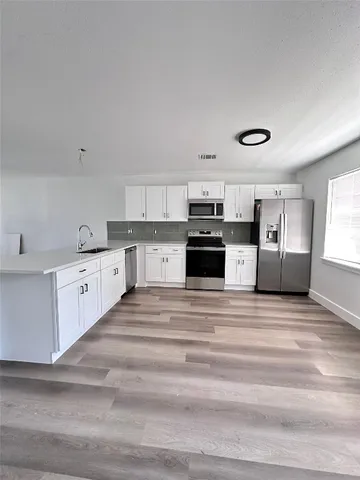 a large white kitchen with stainless steel appliances granite countertop a stove and a sink