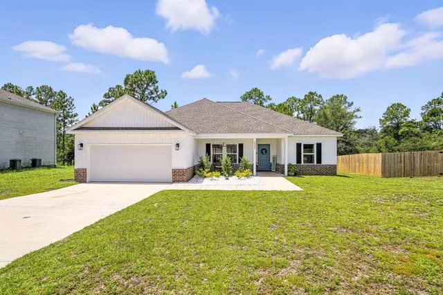 a view of a house with a small yard and a large tree