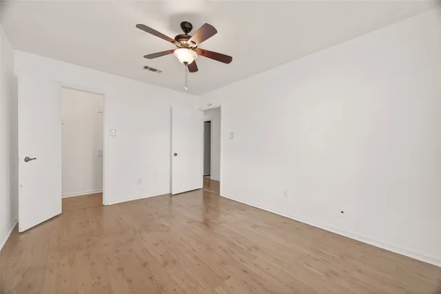 an empty room with a window and a fan