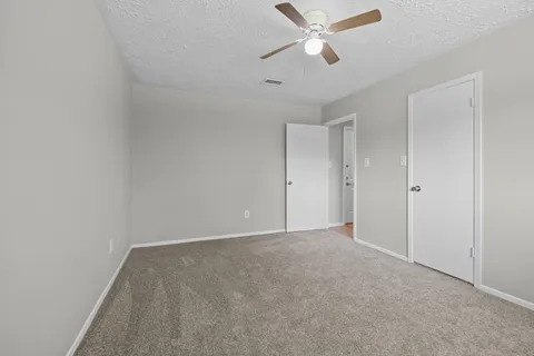 an empty room with a chandelier fan and windows