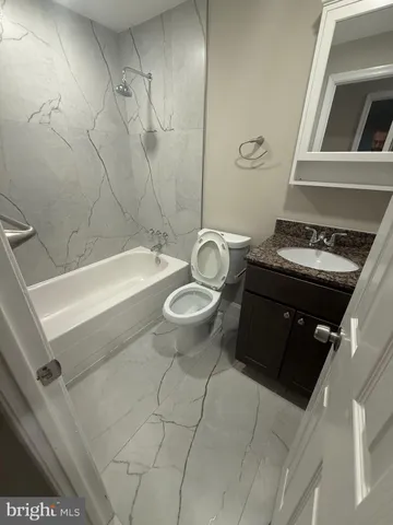 a bathroom with a granite countertop sink a toilet and bathtub
