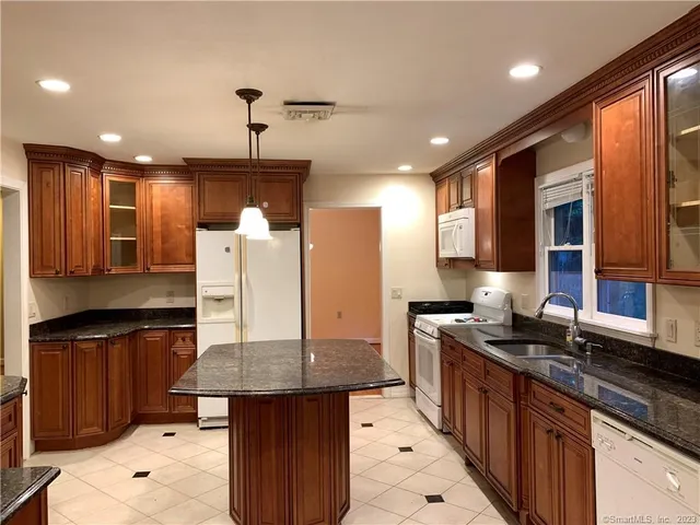 a kitchen with granite countertop a sink a counter space appliances and cabinets