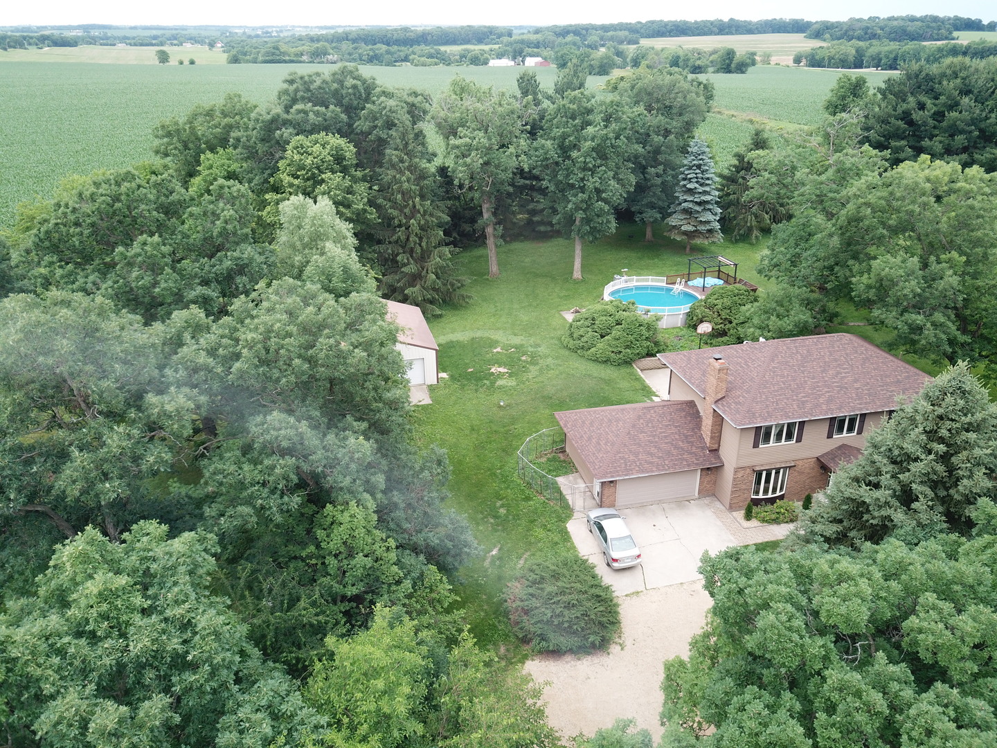 an aerial view of residential house with outdoor space and trees all around