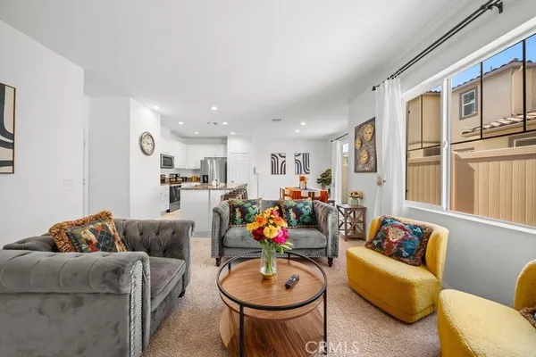 a living room with furniture kitchen view and a chandelier