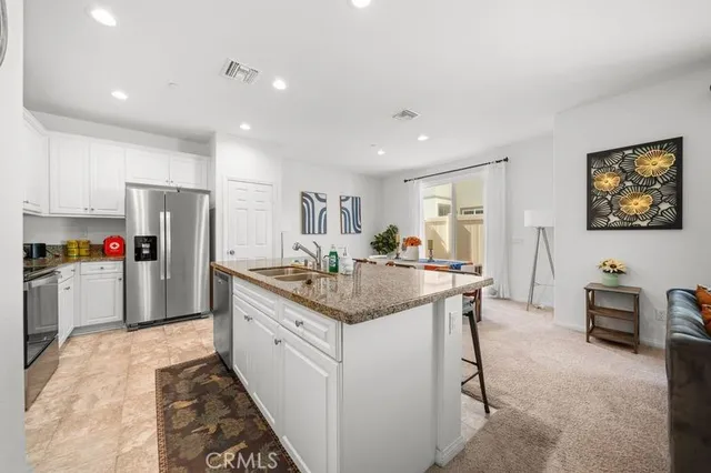 a kitchen with stainless steel appliances kitchen island granite countertop a refrigerator and a sink