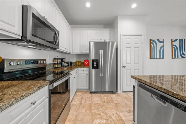 a kitchen with stainless steel appliances granite countertop a stove refrigerator and microwave