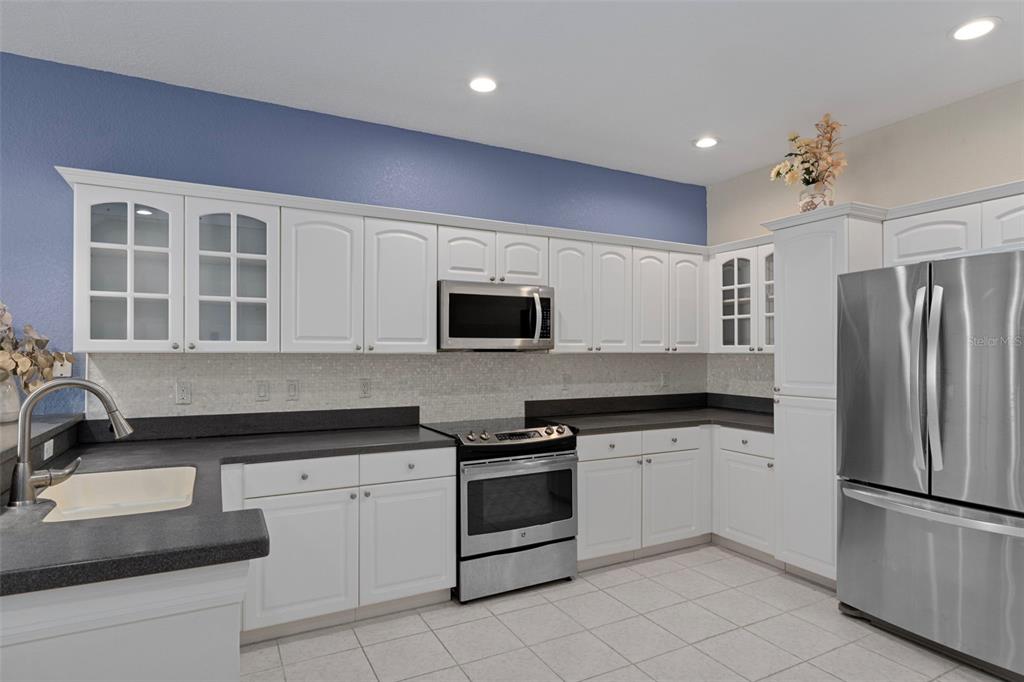 8304 Aquila Street Port Richey, FL 34668 - Photo 18 of 65 a kitchen with granite countertop white cabinets and stainless steel appliances