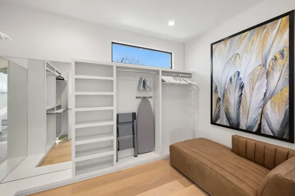 a living room with a couch and a walk in closet with wooden floor