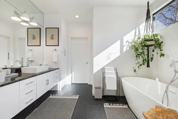 a spacious bathroom with a double vanity sink a large mirror a bathtub and a shower