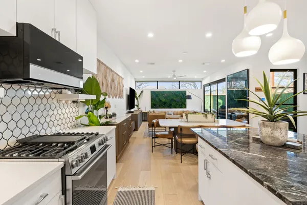 a kitchen with stainless steel appliances granite countertop a sink a stove and a wooden floors