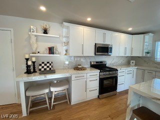 2712 Rialto Road Las Vegas, NV 89108 - Photo 29 of 54 Kitchen featuring appliances with stainless steel finishes, decorative backsplash, white cabinetry, open shelves, and light wood-type flooring