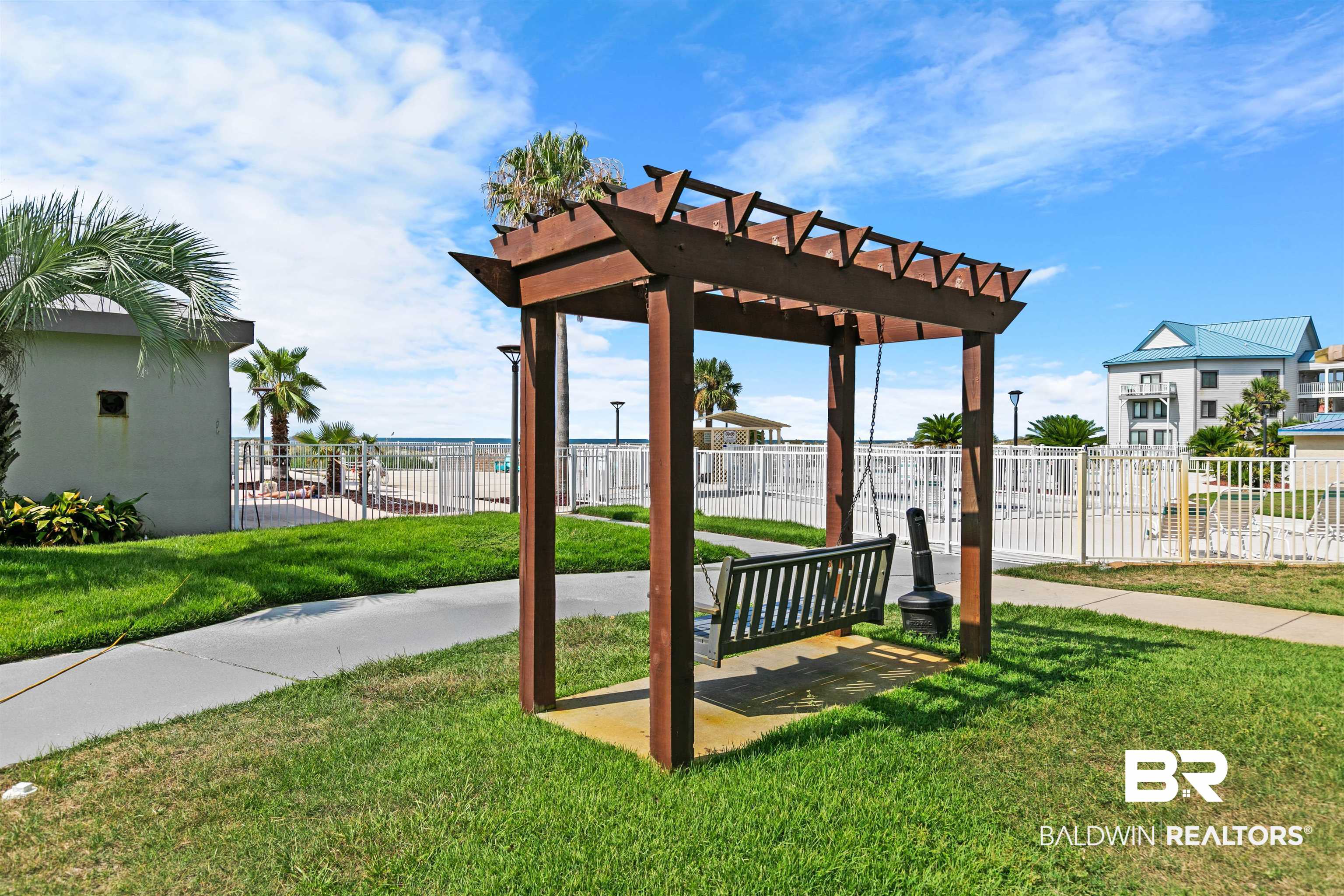 645 Plantation Road, Unit 6606 Gulf Shores, AL 36542 - Photo 56 of 60 Wooden pergola with an attached swing, set on a manicured lawn
