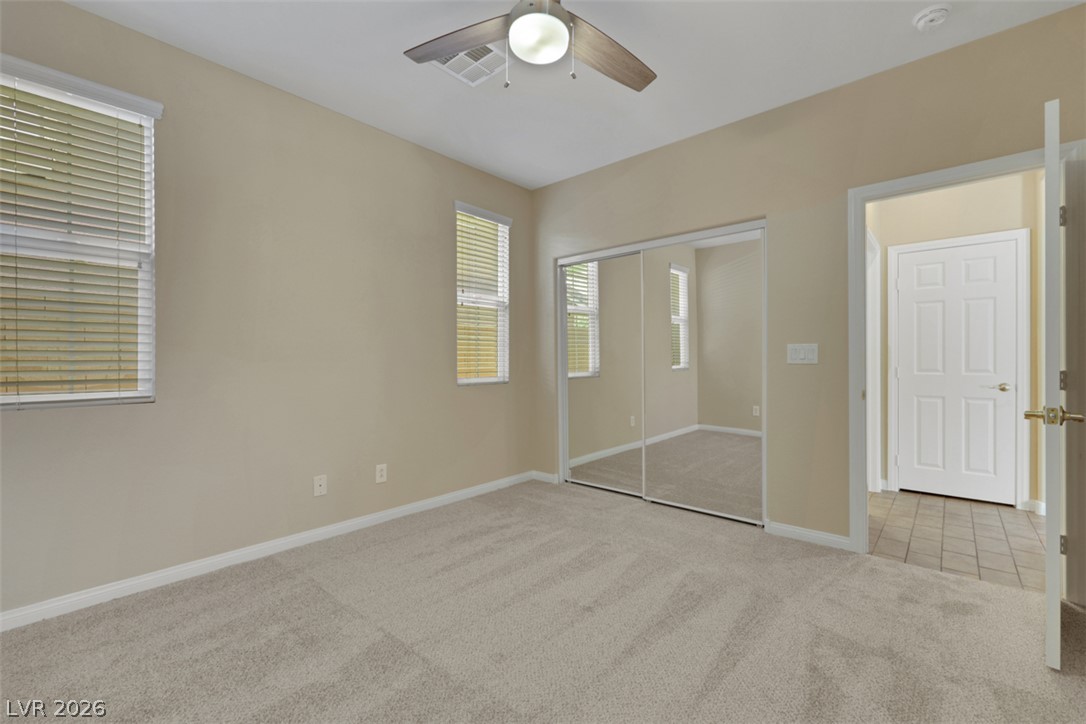 10328 Hawk Ravine Street Las Vegas, NV 89178 - Photo 21 of 55 A well-lit bedroom offering a blank canvas for personalization, complete with a mirrored closet and plush carpeting.