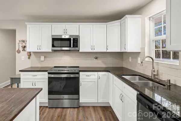 a kitchen with granite countertop white cabinets and stainless steel appliances