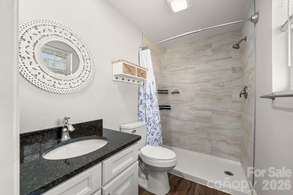 a bathroom with a granite countertop sink toilet mirror and shower