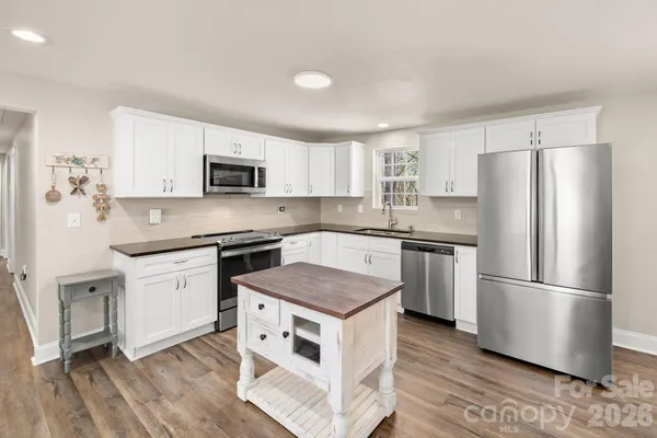 a kitchen with granite countertop white cabinets and stainless steel appliances