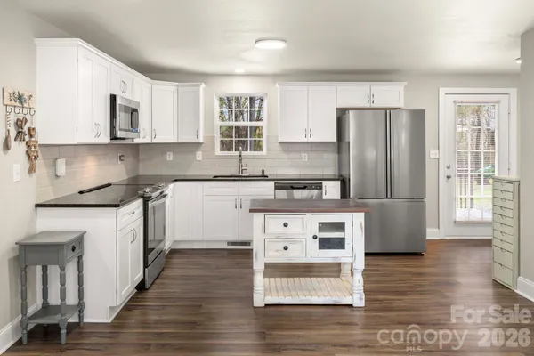 a kitchen with stainless steel appliances granite countertop a refrigerator a stove top oven a sink and dishwasher with wooden floor