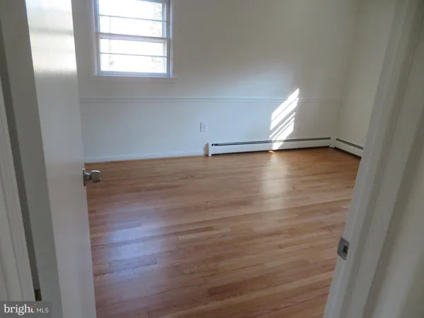 an empty room with wooden floor and windows with curtains