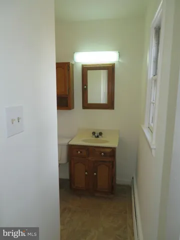 a view of an empty room with mirror and a dresser
