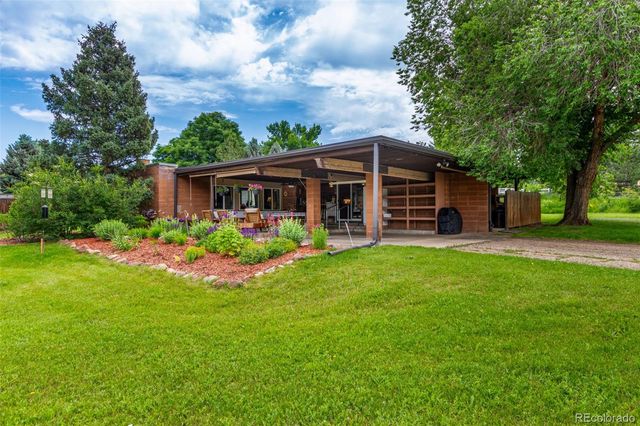 a view of a house with a yard and large trees