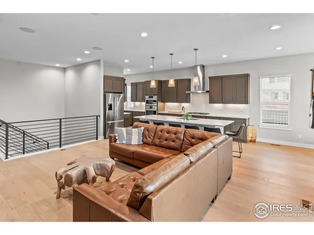 a living room with stainless steel appliances furniture a rug and a kitchen view