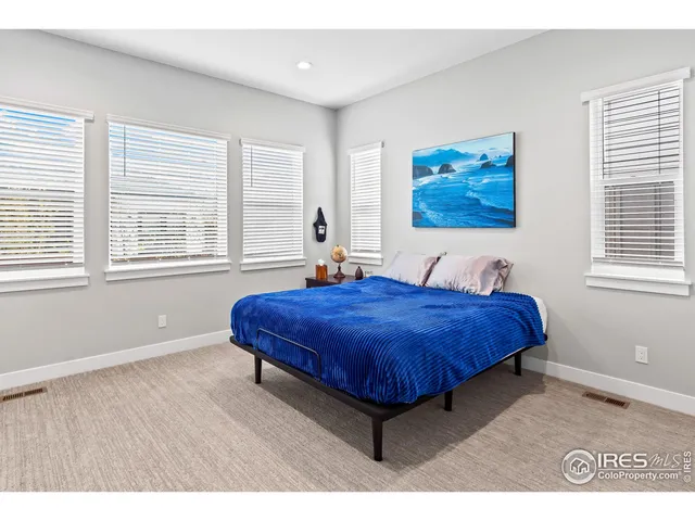 a spacious bedroom with a bed and wooden floor