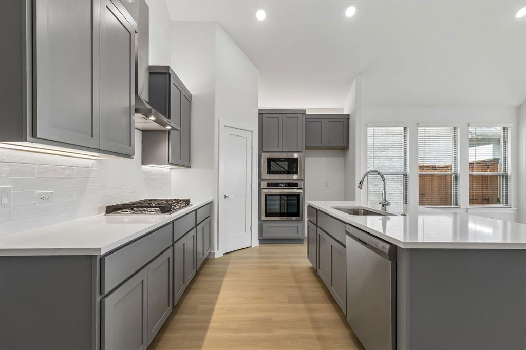 1429 Companero Street Haslet, TX 76052 - Photo 7 of 35 a kitchen with stainless steel appliances granite countertop a stove top oven a sink and dishwasher
