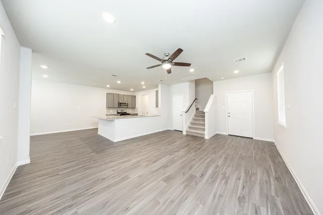 an empty room with wooden floor and a ceiling fan