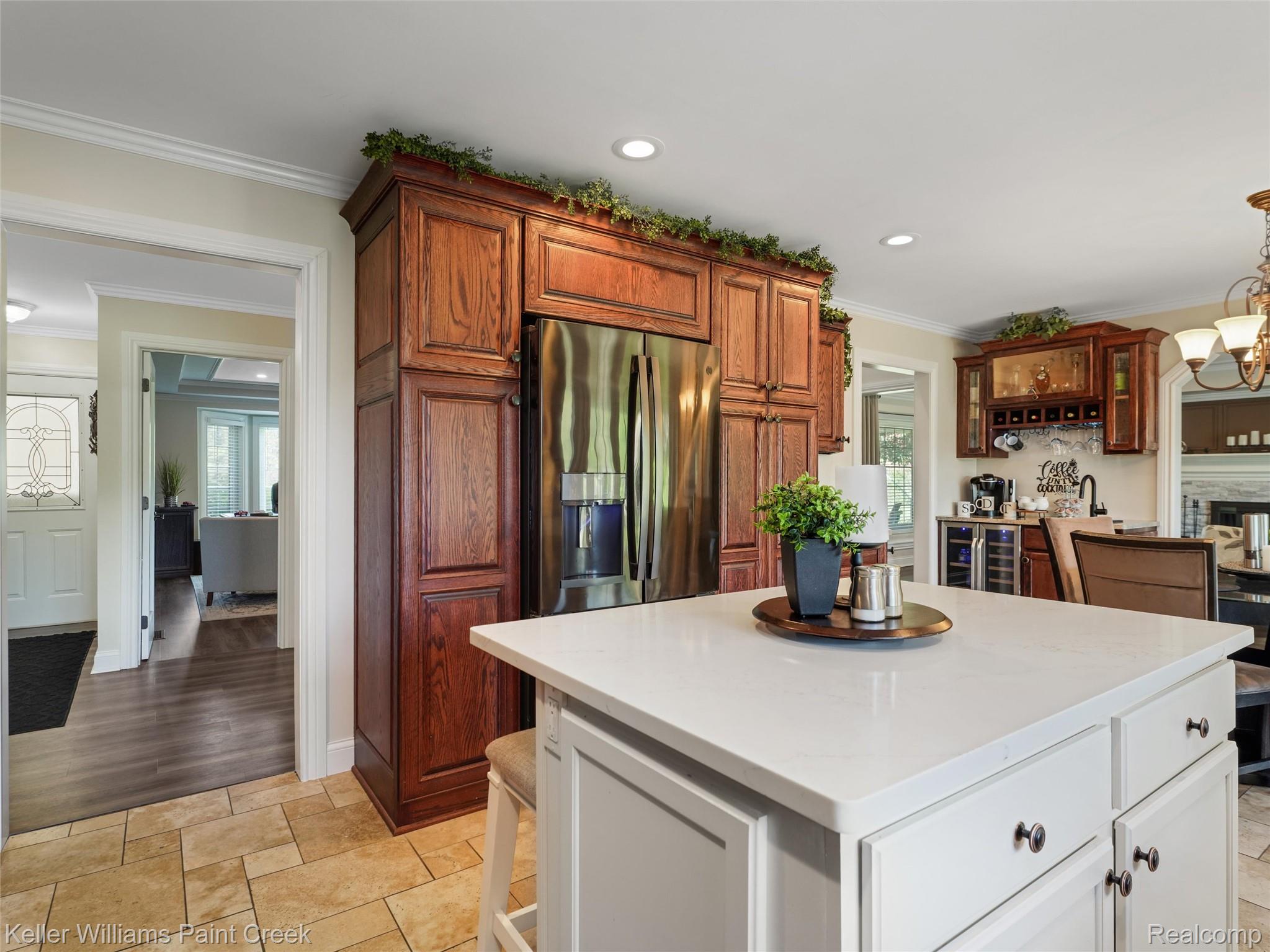 5813 36 Mile Road Romeo, MI 48065 - Photo 11 of 81 Kitchen featuring a substantial island with a light-toned countertop and cabinetry, integrated stainless steel refrigerator, extensive wood-finish cabinetry, a dedicated beverage station with a wine rack, and recessed lighting