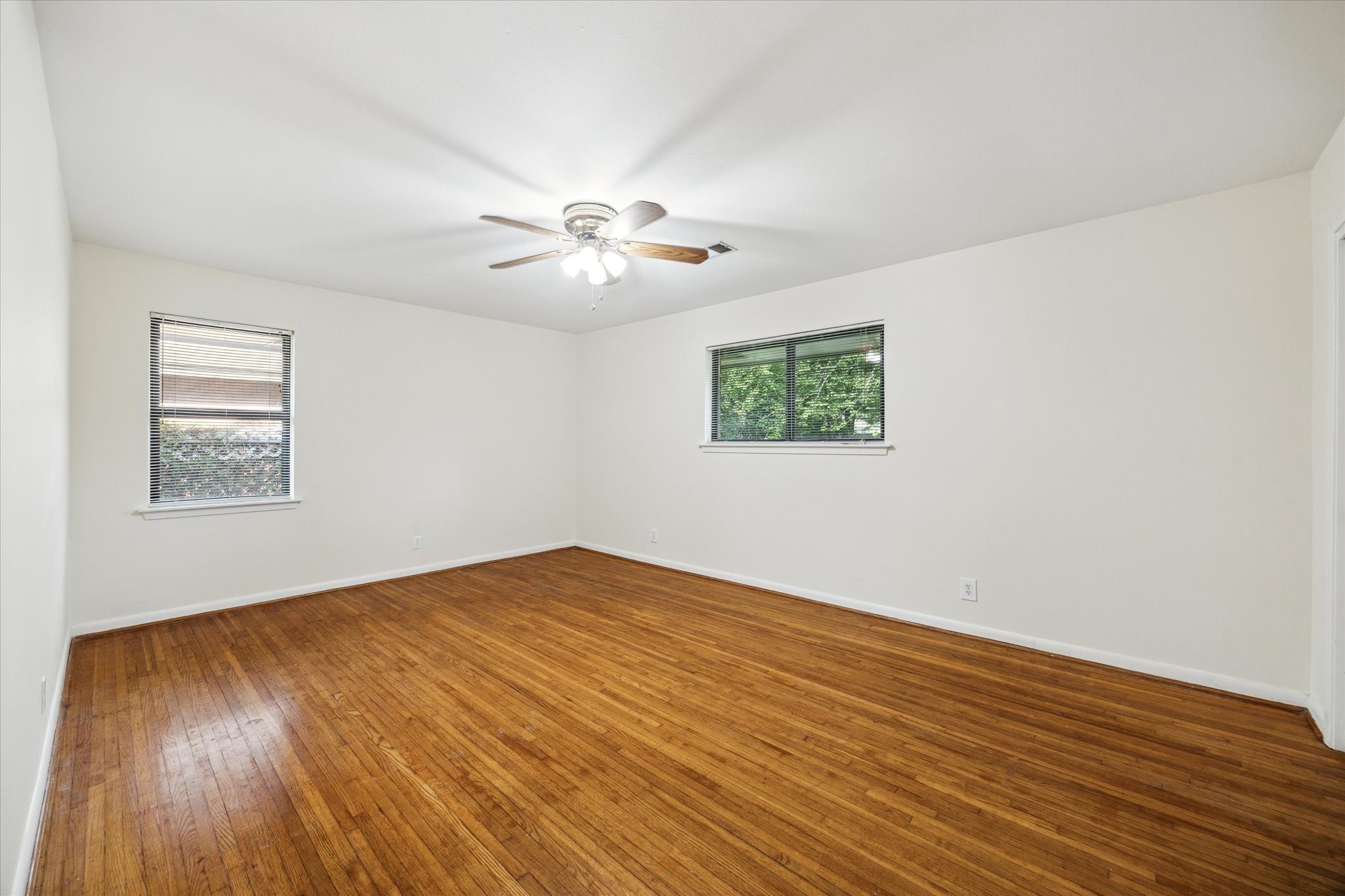 8907 Autauga Street Houston, TX 77080 - Photo 15 of 20 This room features hardwood flooring, neutral walls, and two windows allowing natural light. A ceiling fan provides air circulation, making it a bright and inviting space.