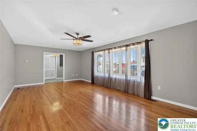 a view of an empty room with a window and wooden floor