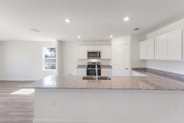 a kitchen with stainless steel appliances granite countertop a sink and a stove top oven
