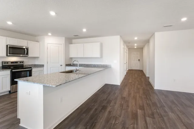 a kitchen with granite countertop a sink cabinets and stainless steel appliances