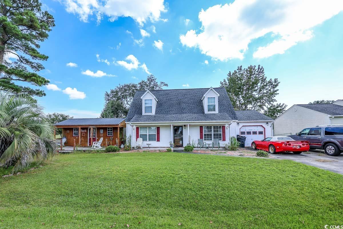 210 Rail Street Longs, SC 29568 - Photo 1 of 32 New england style home with asphalt driveway, a front lawn, an attached garage, covered porch, and roof with shingles