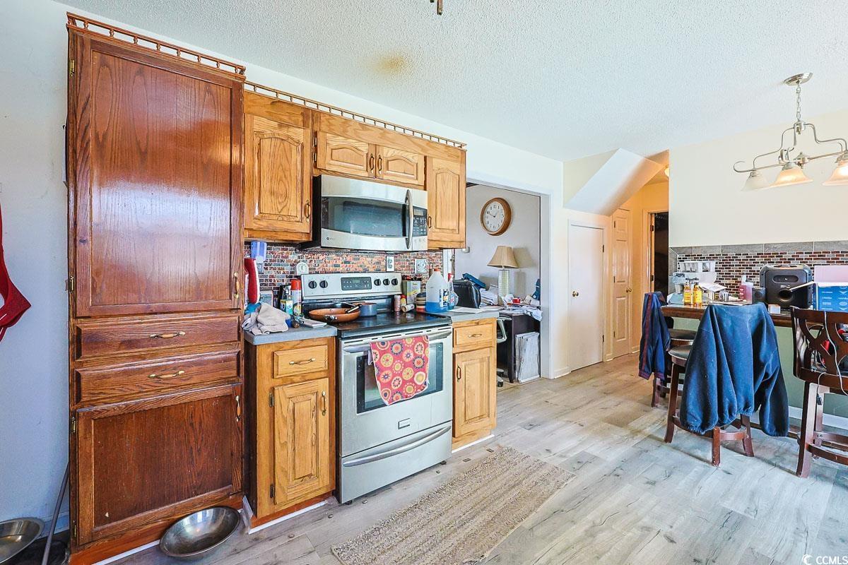 210 Rail Street Longs, SC 29568 - Photo 11 of 32 Kitchen with appliances with stainless steel finishes, tasteful backsplash, light countertops, light wood-type flooring, and a textured ceiling