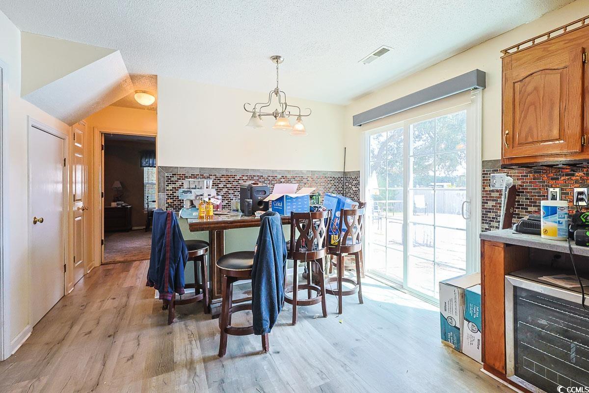210 Rail Street Longs, SC 29568 - Photo 10 of 32 Dining space with light wood-style floors, a textured ceiling, and a chandelier